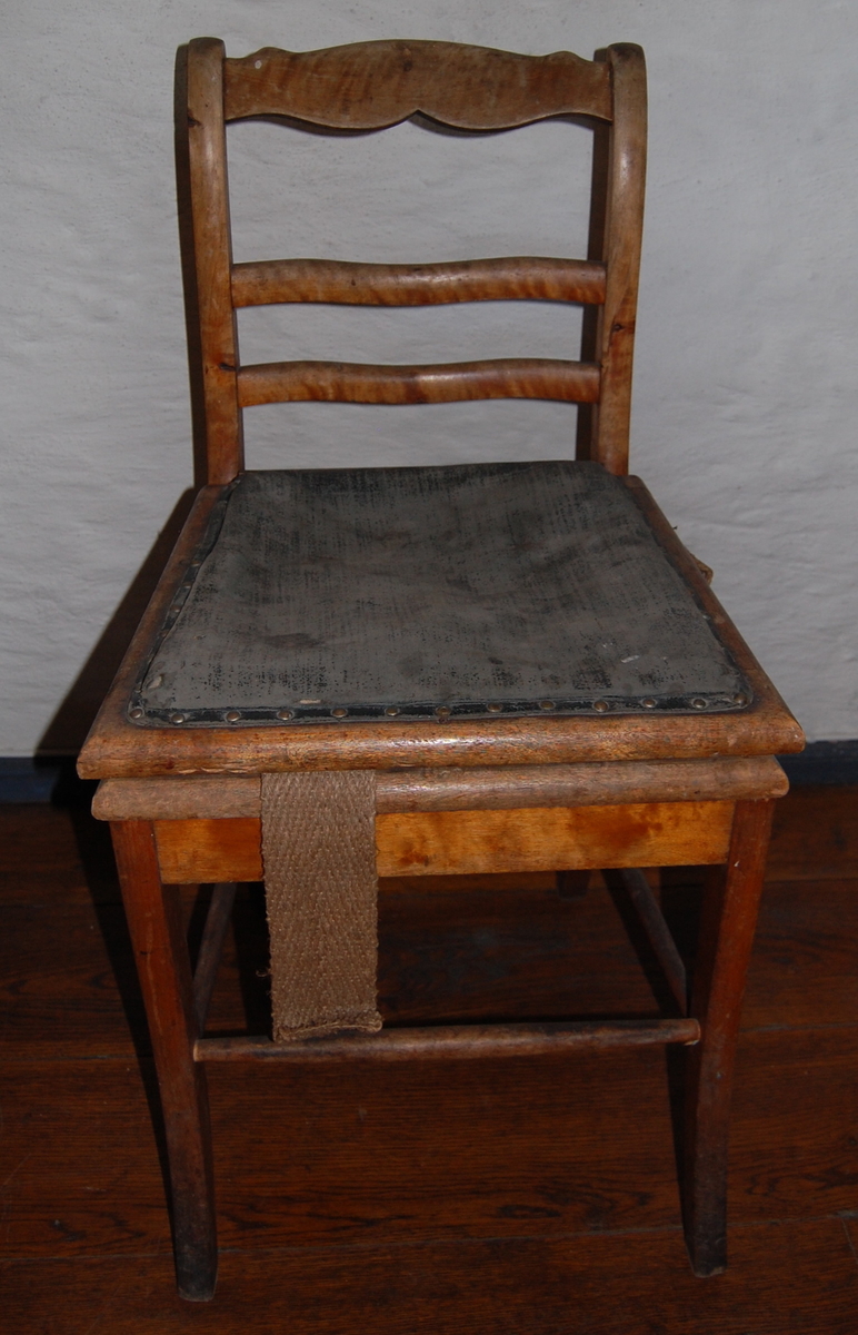 Trestol med sete i kunstskinn (?). Tre ryggsprosser, den øverste profilert. Likner AS.613-617, Biedermeier-stil. Løse bakben. Et ekstra sete fra en annen ukjent stol. 