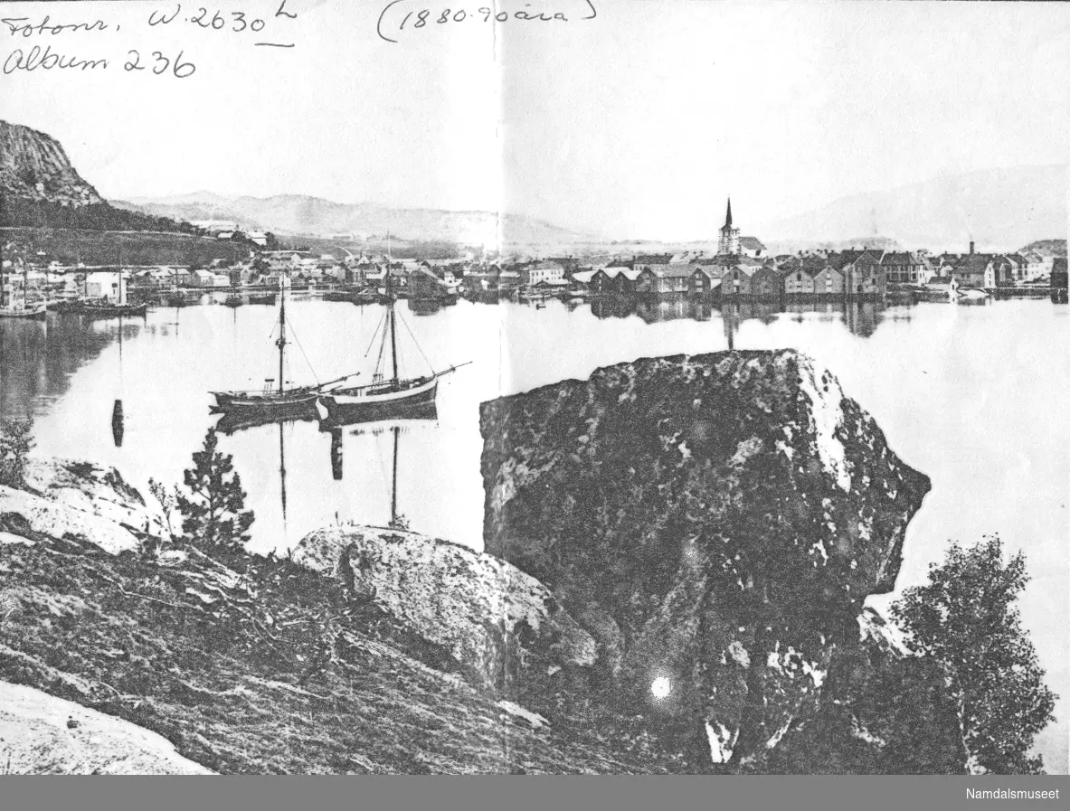 Båtbilde, Namsos. To båter med seil. Byen i bakgrunnen.