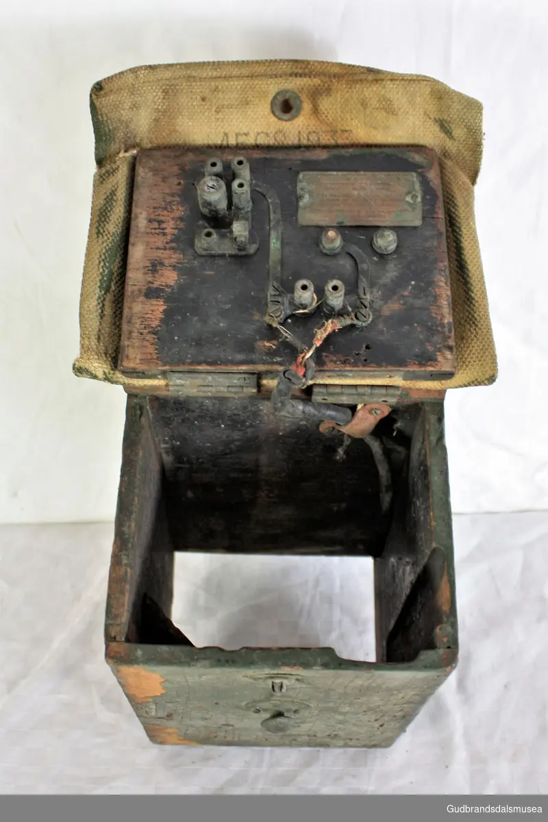 Trekasse med lokk, dekt med web.
Kassen ble brukt til oppbevaring av batteri og morsenøkkel for signallykt.
Kassen er delt i to rom.
Merket 1933.
Gjenstanden ble funnet i Kvam, Gudbrandsdalen.