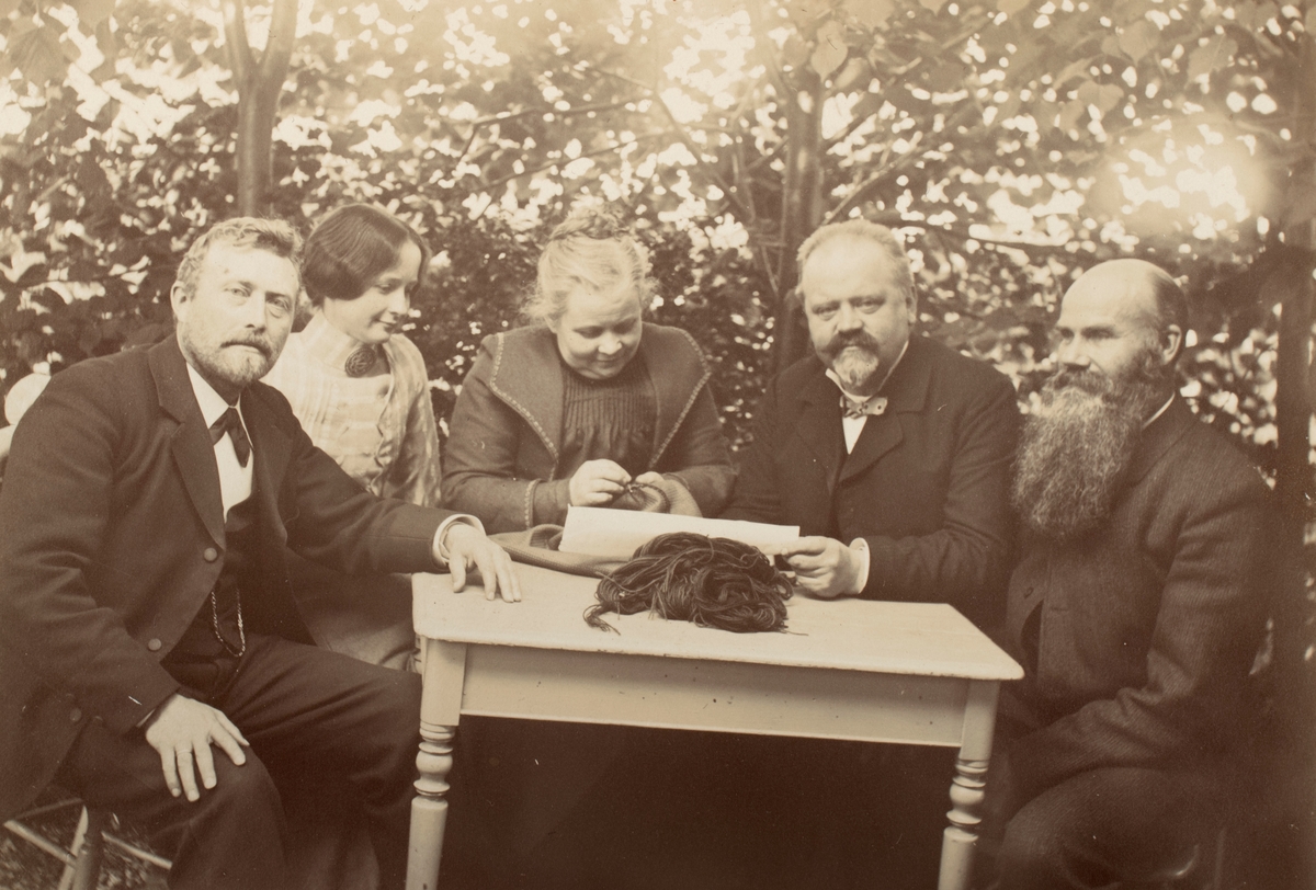 Gruppeportrett av fem personer rundt et bord i hagen.