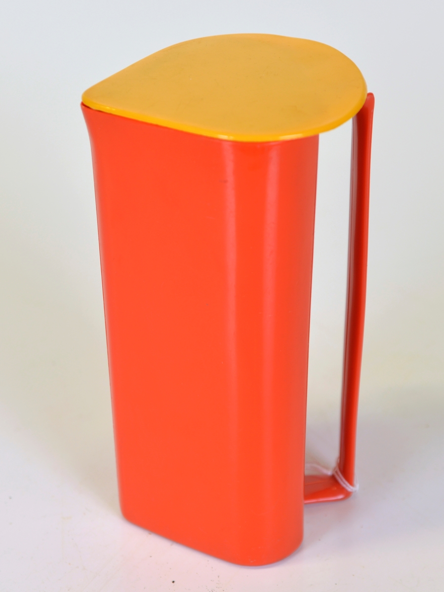 
Trekantig juicekanna med rundade hörn. Handtaget längs hela kannans längd. Orange hårdplast med gult lock. Populära färger på 1970-talet.