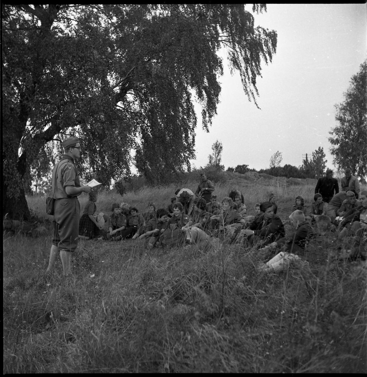 Scouter samlade i gräset fram en ledare, möjligen i Alviken.