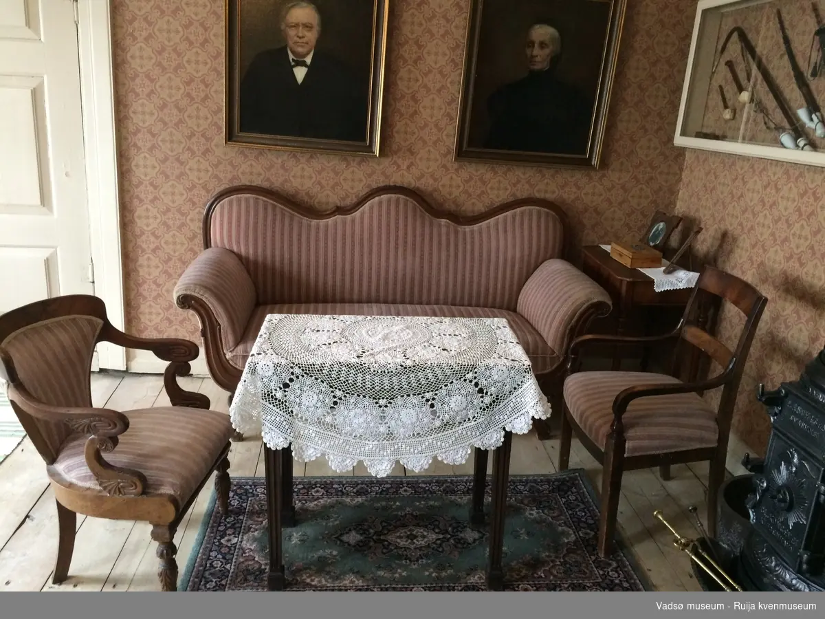 Rektangulær sofa i Biedermeier-stil. S-formet ryggbrett. Glatt, profilert rygglist. S-formede utoversvungne lener og lett utoversvungne bein. Lener, nedre kant av sargen og sofabeina er dekorert med utskåret blad-/knoppedekor. Sofaen er stoppet og er trukket i rosa, hvitstripet stoff.
