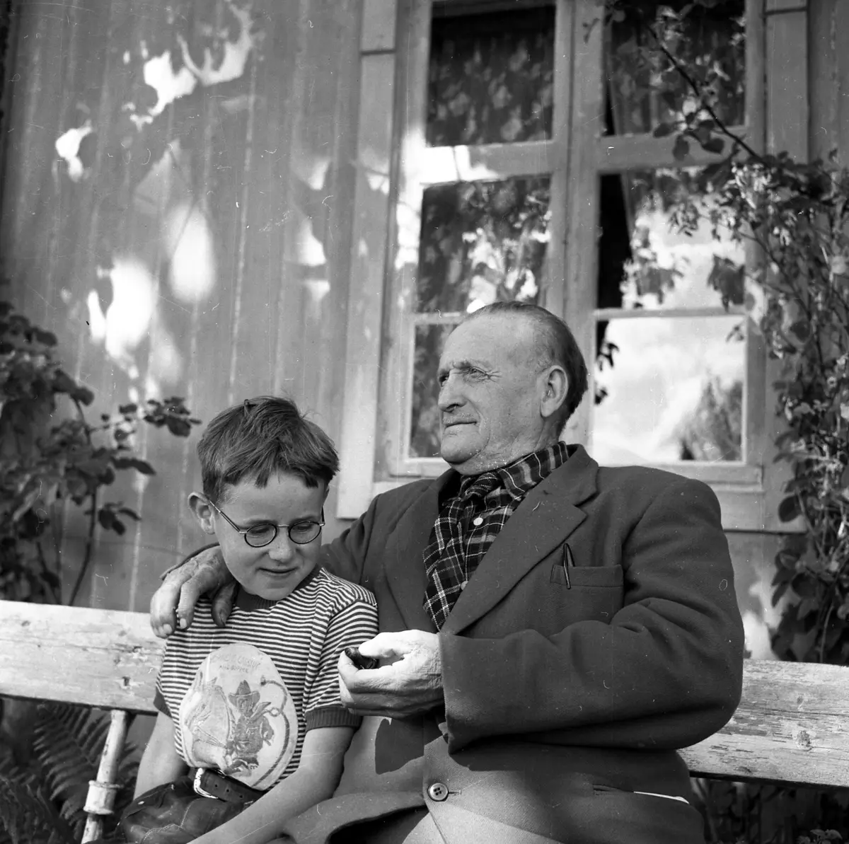 Conrad og Knut Fjeld på Nordby gård. De sitter på en benk utenfor huset