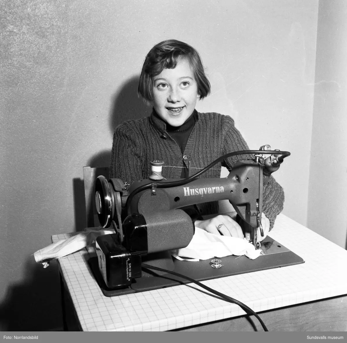 En ung flicka syr på en symaskin.
