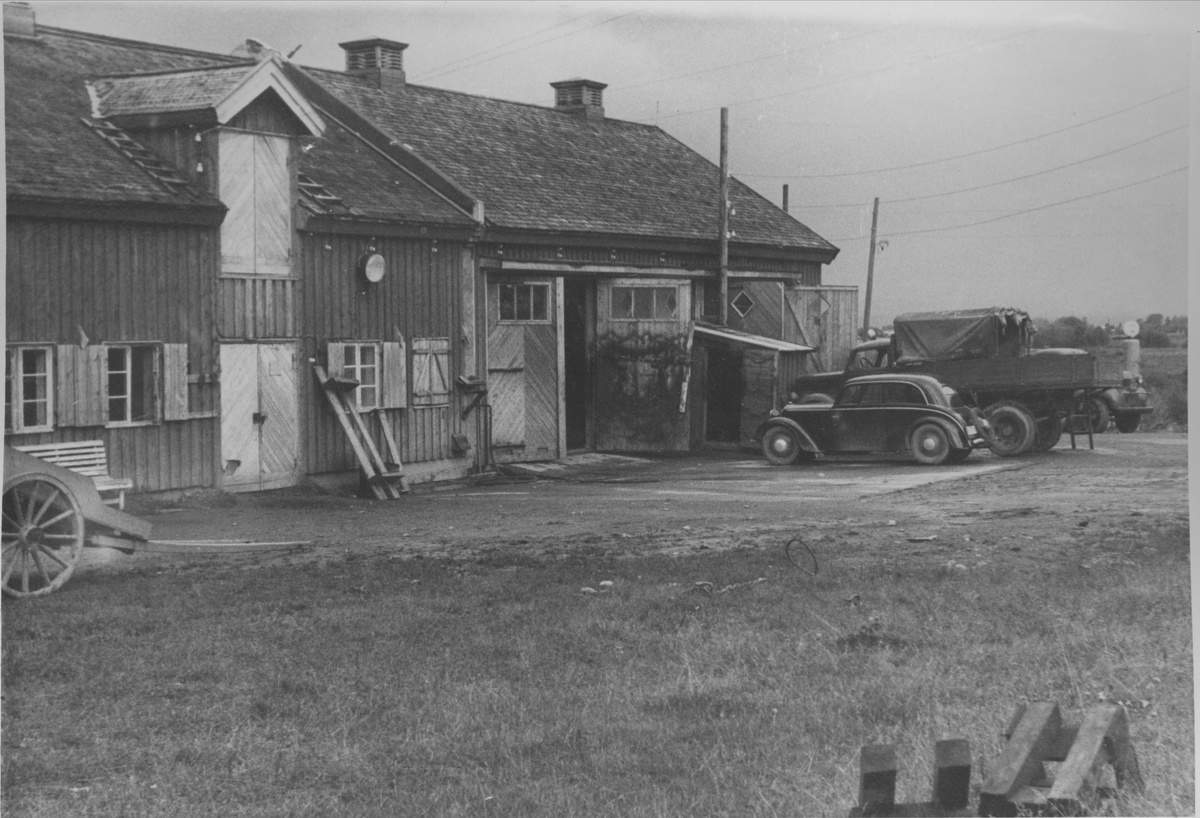 Innherad fangeleir (tvangsarbeidsleir). Leirens bilverksted. Bygningen er oppført for SS Strafgefangenlager Falstad 1942-43, med garasje/bilverksted til høyre og fjøs/stall til venstre, skilt med en brannmur. Personbilen er av merket DKW.