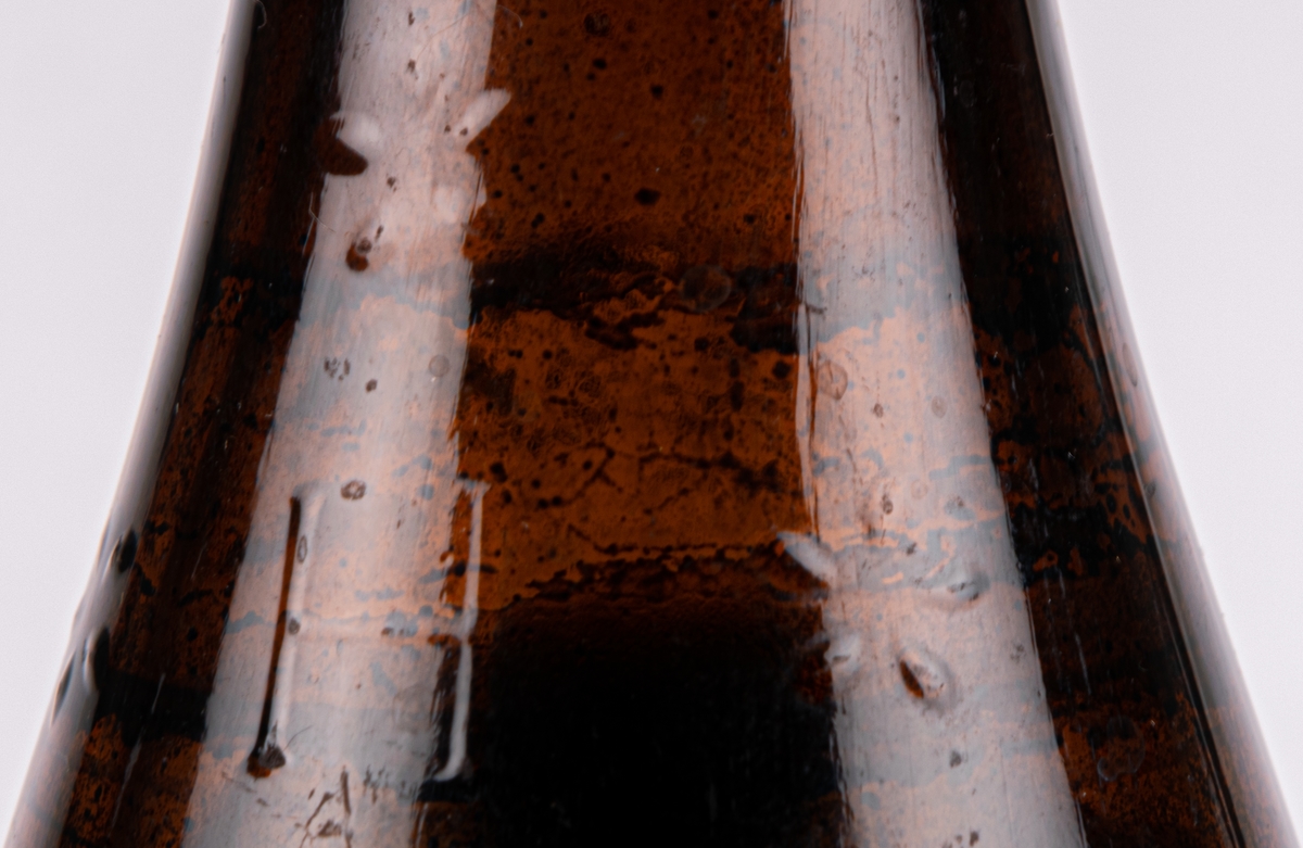 Flaska av brunt glas, med China-varnish. Plomberad med innehållet kvar.
Bästa fernissa för alla läder-, trä, metall-, korg-, och sadelmakeriarbeten, stråhattar m.m.