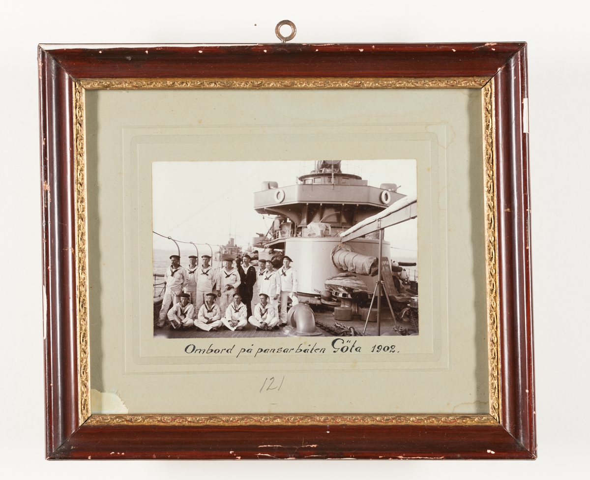 Denna grupporträtt föreställer manskap kläd i vita sjömanskostymer ombord på pansarbåten Göta 1902.