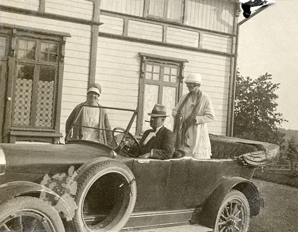 Två kvinnor, en man och en bil av märket Hudson, framför ett bostadshus.

Jfr Alb12-136 och 138.
