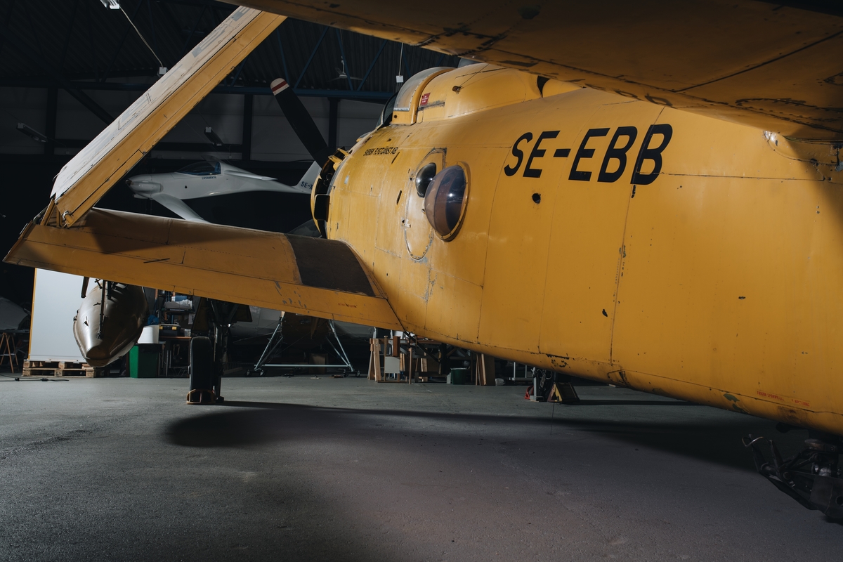 Flygplan av modell Skyraider. Enmotorigt propellerflygplan ursprungligen avsett för basering på hangarfartyg. Gulmålat, något nött med genomslag av Royal Navys marinblå kamouflage. Märkning på flygkroppens sidor: "Svensk Flygtjänst AB".