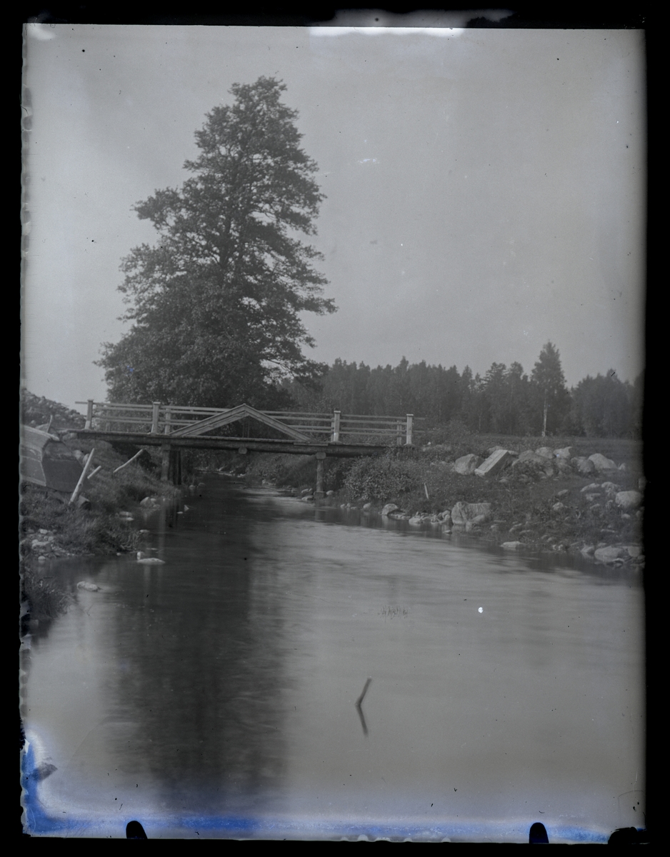 Landskap med vattendrag och bro, ca 1910.