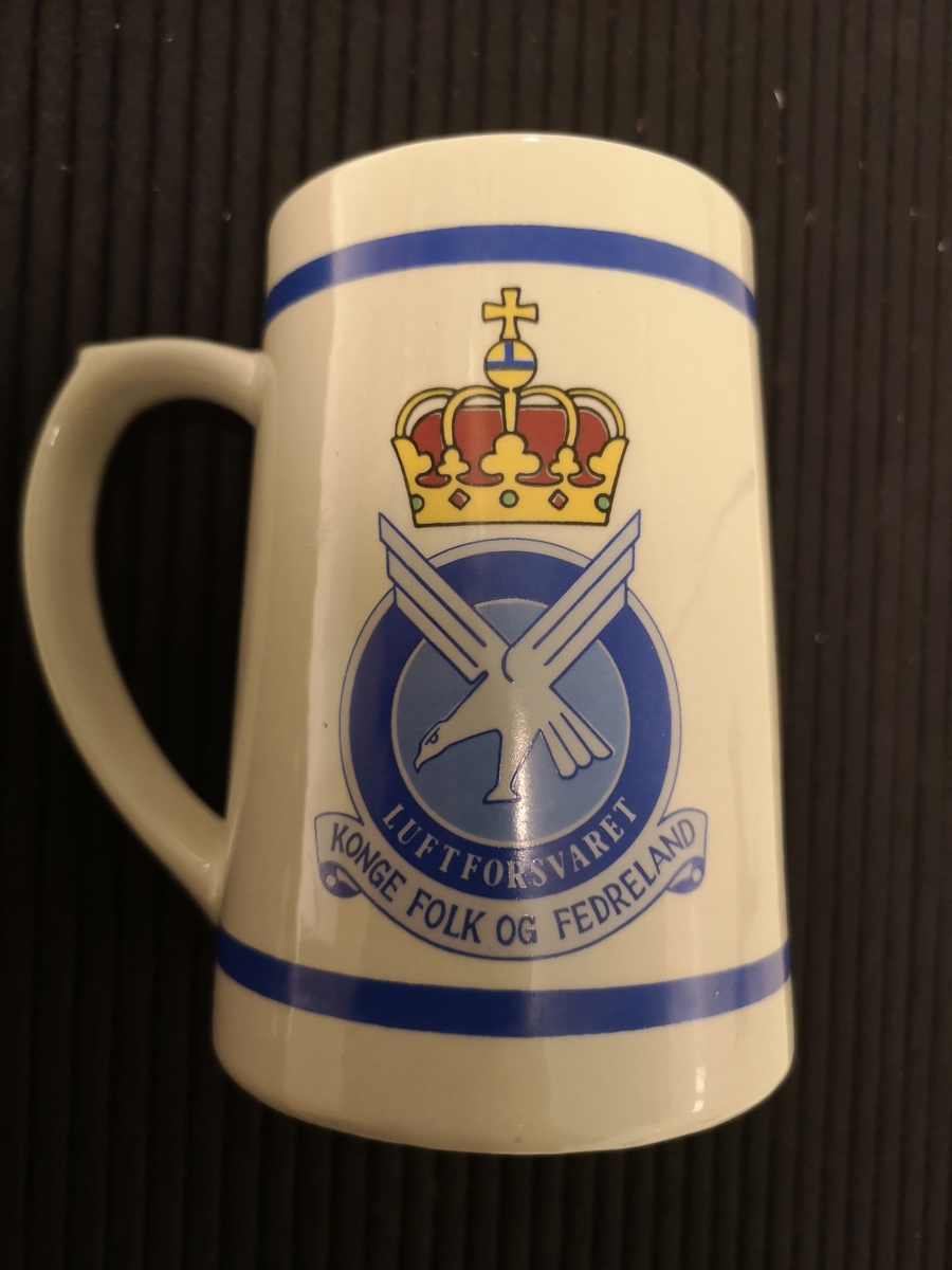 Luftforsvarets emblem på baksiden.
3 varder og tekst "Vi Vokter" på forsiden.