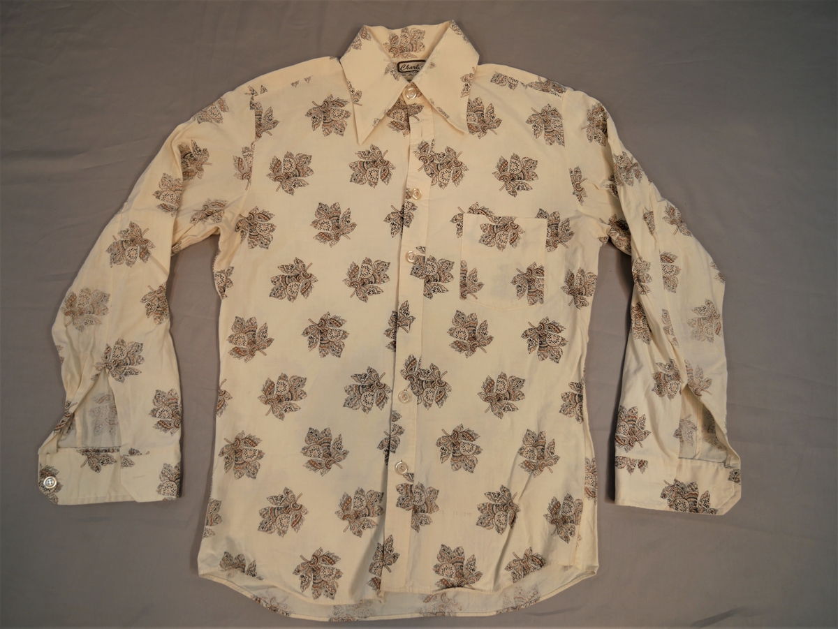 Slim herreskjorte med spiss krage, stolpe med 7 knappar (2 manglar) brystlomme. Mønster med lauv over heile skjorta.