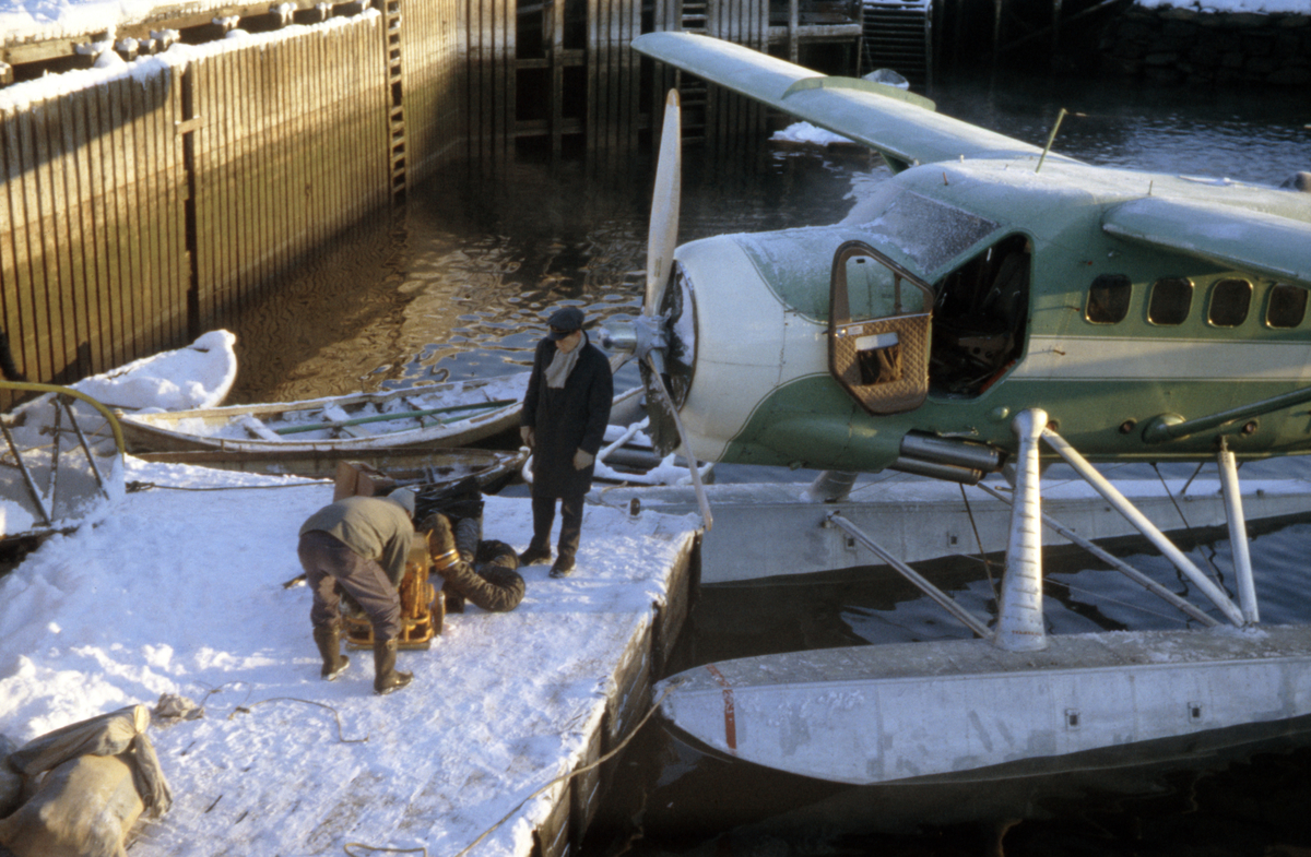 Widerøes DHC-3 Singel Otter, LN-BIB ligger til kai i Kirkenes. Det er vinter og kaldt og mannskapet varmer opp flyets motor med ved hjelp av en generator.