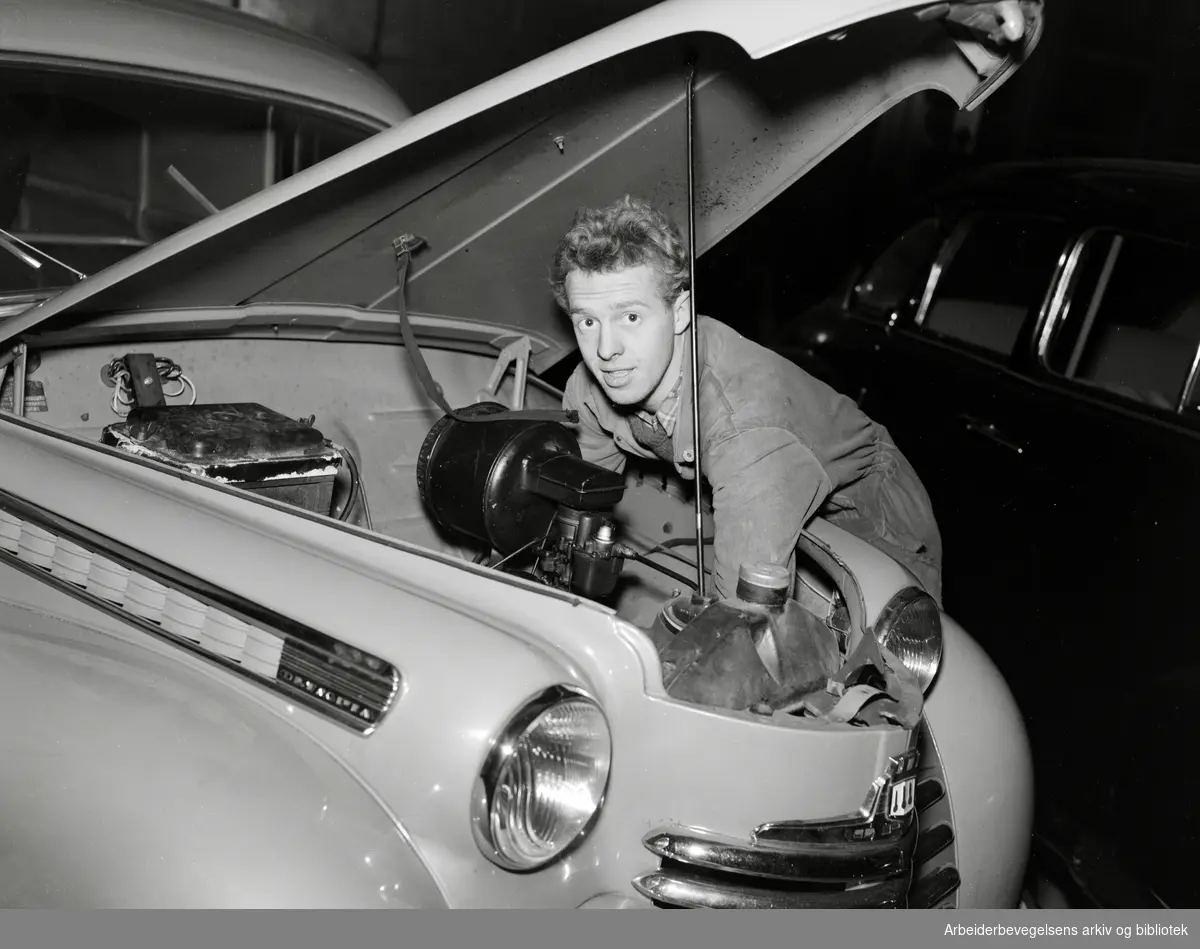 Bilmekaniker Arne Christoffersen ved Christiansen & Co's bilverksted i Industribygget på Nedre Sinsen. Opel Olympia. November 1951.