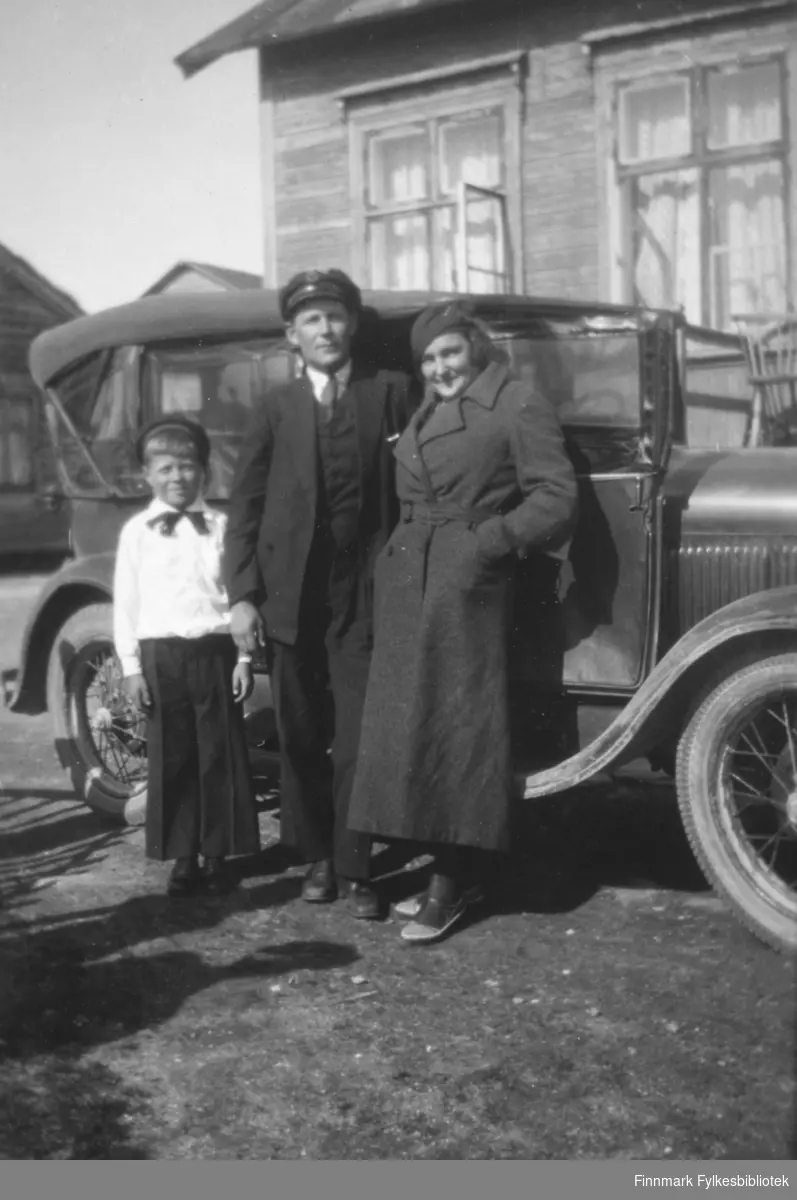En familie fotografert ved siden en bil og hus. Stedet er mest sannsynligvis Salttjern.