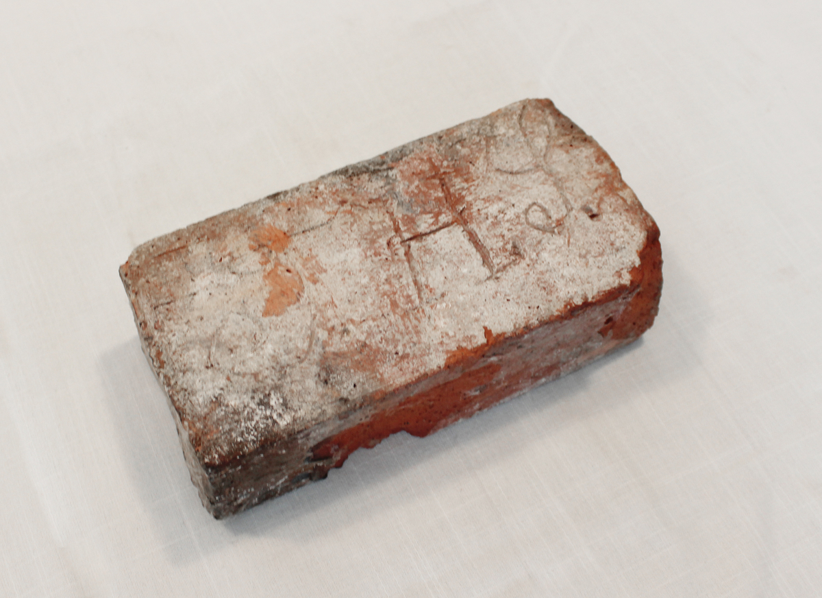 Keramisk murstein med uklar innskrift. Usikker opprinnelse og datering.