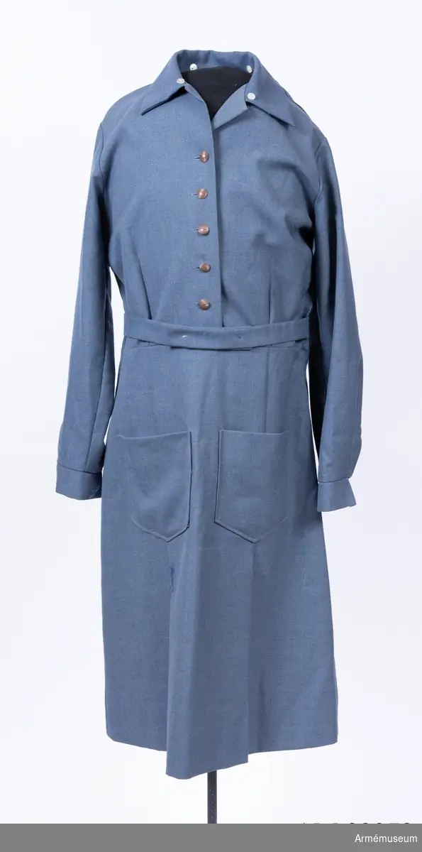 Rockklänning av mörkblått ulltyg med knappar för Svenska Blå Stjärnan. Med skärp i samma tyg. Krage och manschetter saknas.