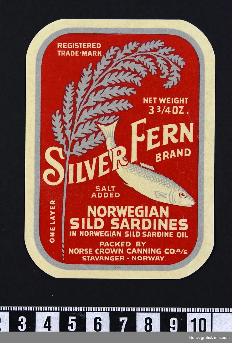 Ræd etikett med bild eav en bregne i sølv/ grå og en fisk. 

"Norwegian sild sardines in Norwegian sild sardine oil"