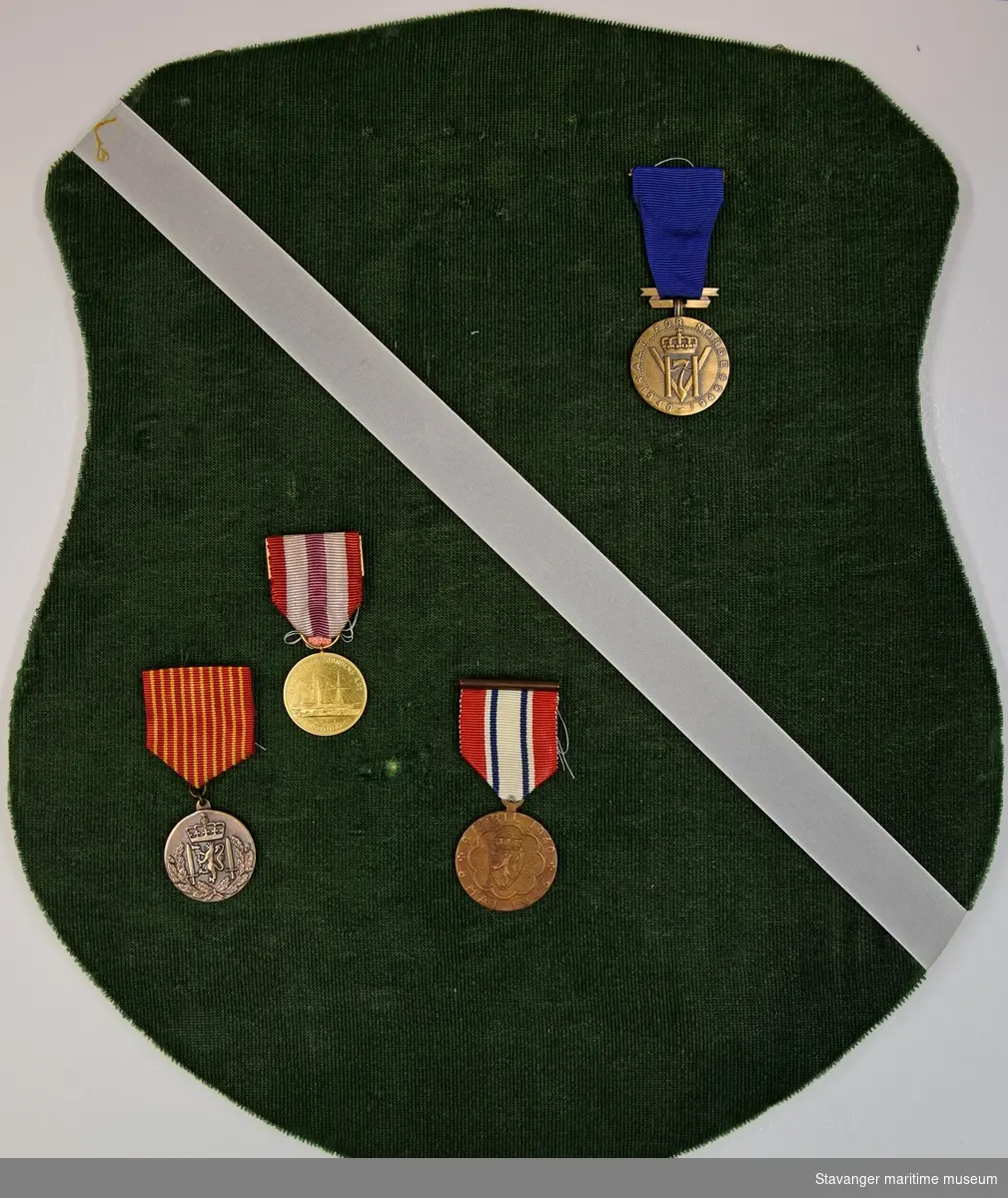 Plate, trolig av spon, kledd i grønn fløyel med hvit tekstilbånd som har metall oppheng, hvor Einar Martin Walviks fire medaljer var montert.