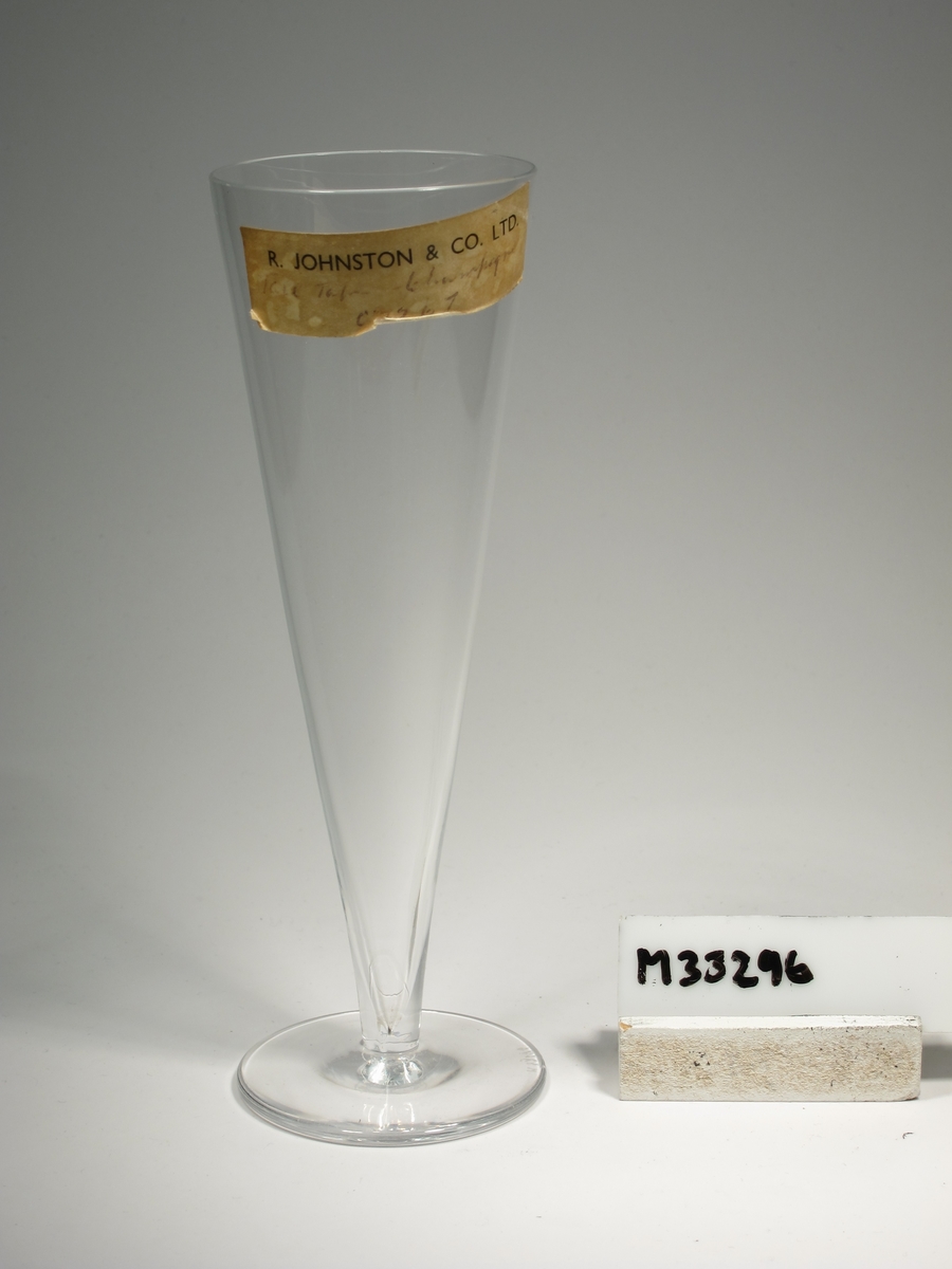 Champagneglas med konisk kupa och påklippt ben.
Etikett: "R. JOHNSTON & CO. LTD.
??? Champagne
C 7267"