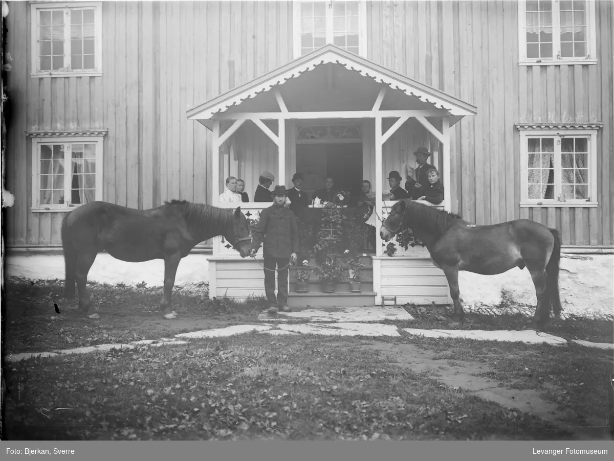 Famile foran huset med hestene på gården.