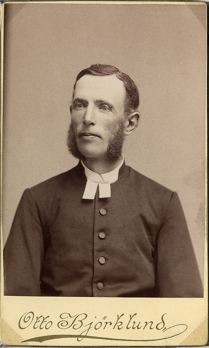 Foto av en man med polisonger, klädd i prästrock med stärkkrage och prästkrage.
Bröstbild, halvprofil. Ateljéfoto.