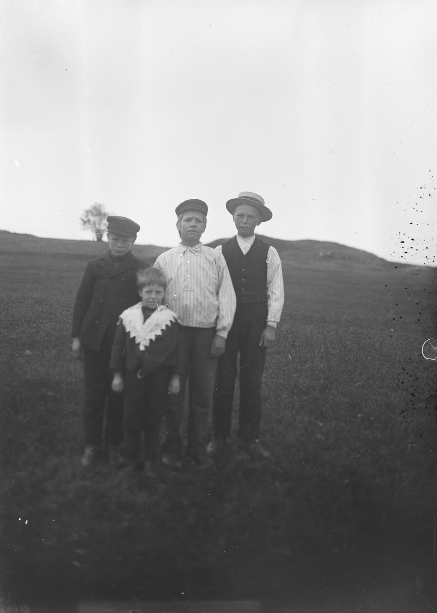 Gruppeportrett av fire gutter på ei mark.