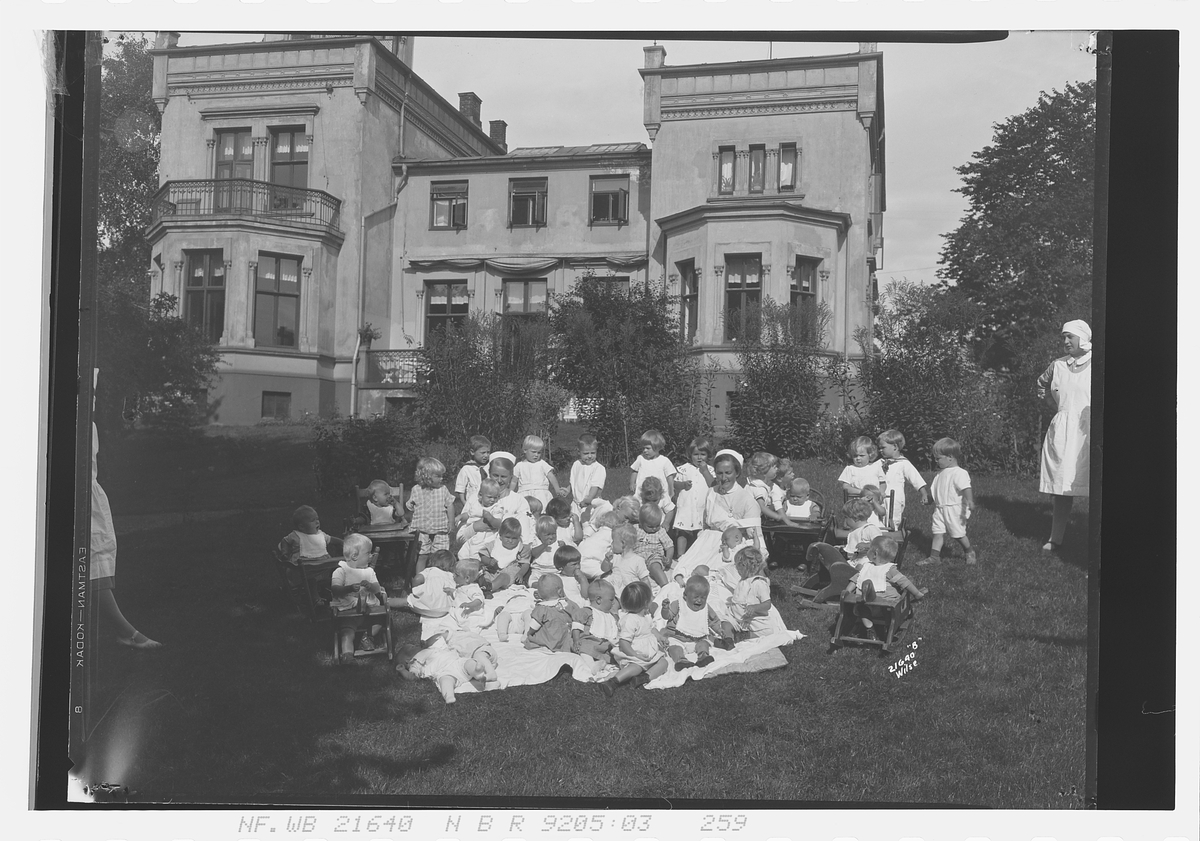 Barn sitter på plenen foran Spedbarnhjemmet, Åkebergveien 23, Oslo. Fotografert 1928.