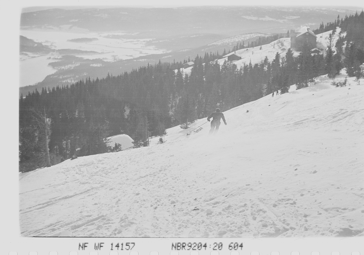 Utsikt fra slalåmløypen på Norefjell med skiløper i bakken. Krødsherad, Viken. Fotografert 1941.