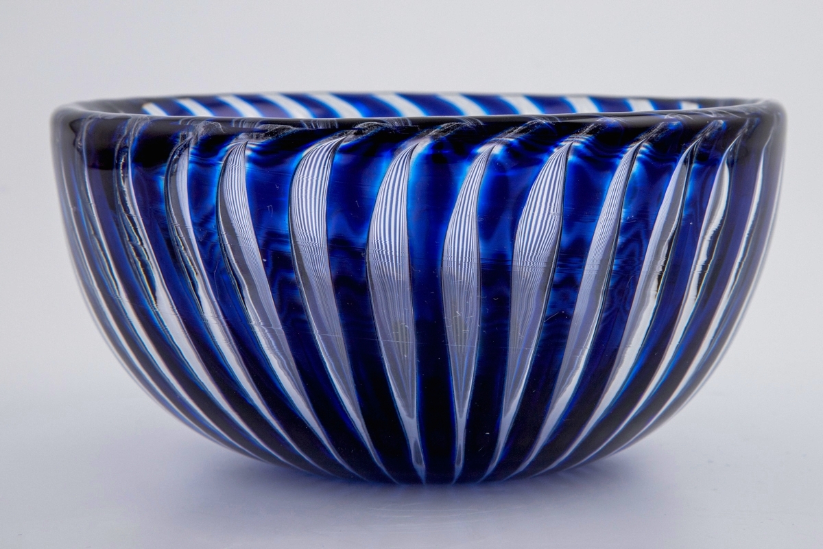 Skål i "Ariel-glas", bestående av tykt klart og blåfarget glass. De radielle blå stripene stråler ut fra skålens bunn, og deres fargenyanser skifter fra sort til himmelblå. Luftbobler mellom stripene.