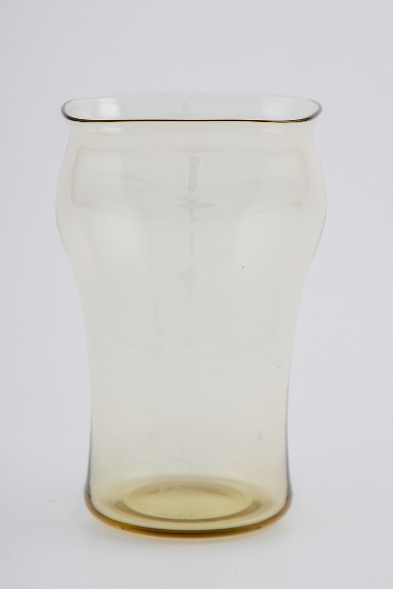 Vannglass. Glasset er utført i olivengrønnfarget gjennomskinnelig glass. Nedre del av korpus er sylinderformet, mens munningen er kvadratisk med svakt konvekse sider.