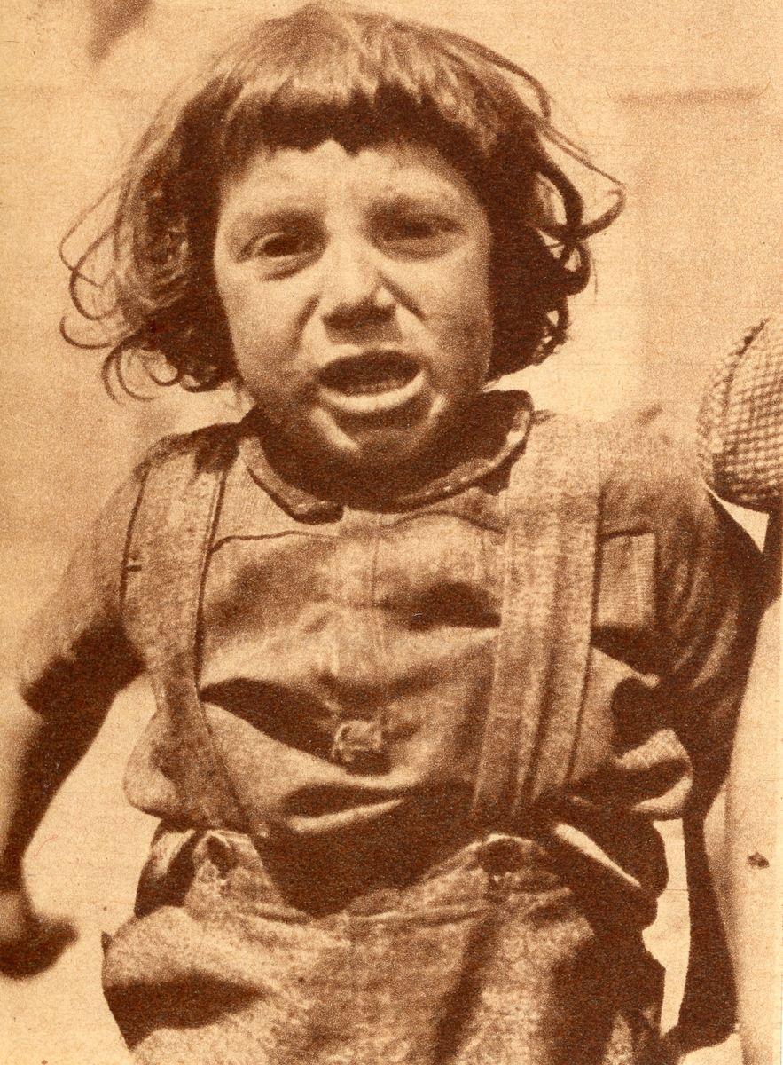 Ett litet barn tittar in i fotografens kamera. Bildens ursprung är okänt.