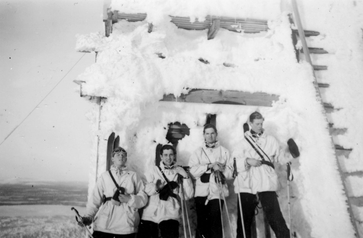 Vila i solen under skidåkning i fjällen, 1944. Fyra militärer i vinterklädsel vilar vid ett plank utanför Gällivare. Under övning i Gällivare.