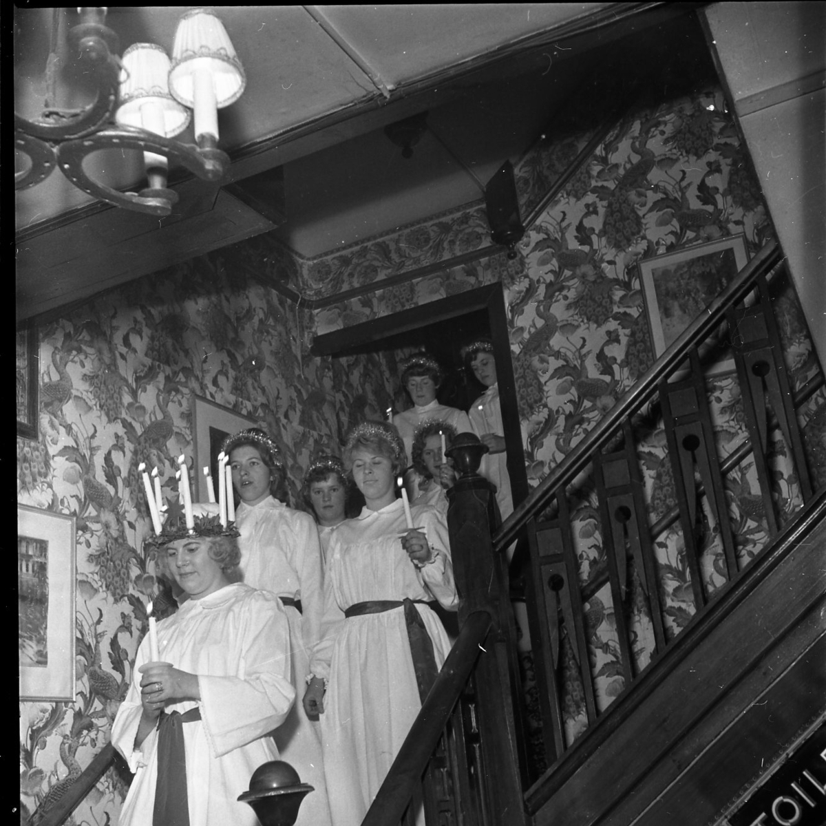 Lucia med sina tärnor i trappan på Ribbagården, på väg ner till bottenvåningen. Bakom Lucia går Gerd Lago och Inger Johansson. Bakom den senare Monica Johansson.