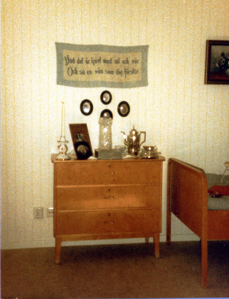 Brattåsgården vid invigningen år 1986. Utställning av föremål från gamla Brattåshemmet, gjord av Kållereds Hembygdsgille. Delar av föremålen finns nu på Mölndals stadsmuseum. Här ses en byrå, del av säng, väggbonad och tavlor.