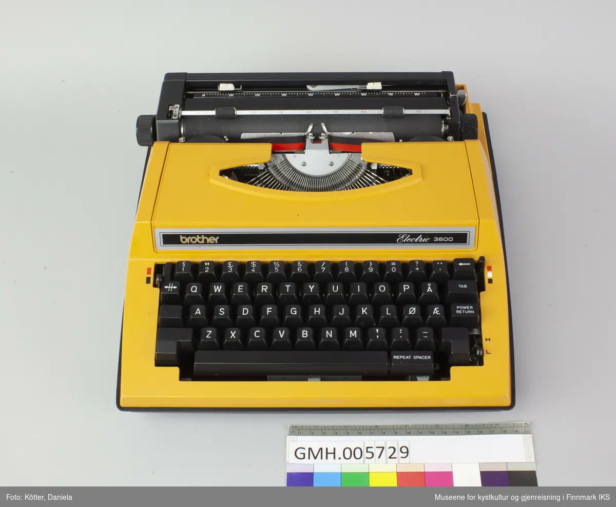 Dette er en elektrisk skrivemaskin med en korpus av oransje og svart kunststoff. Maskinen fungerer. Den kan brukes for papir opp til A4-format og brukes med tofarget bånd, slik at bokstavene kan skrives i svart eller rødt. Til transport, kan det settes det på et lokk av svart kunststoff.     