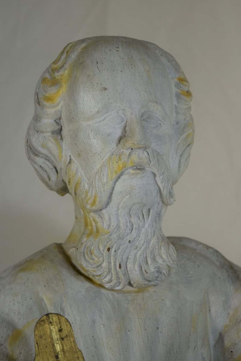 Evangelisten Matteus, stående på høyre ben med engelen ved kneet, oppslått bok på venstre arm. Kappen danner bakgrunn for figuren.