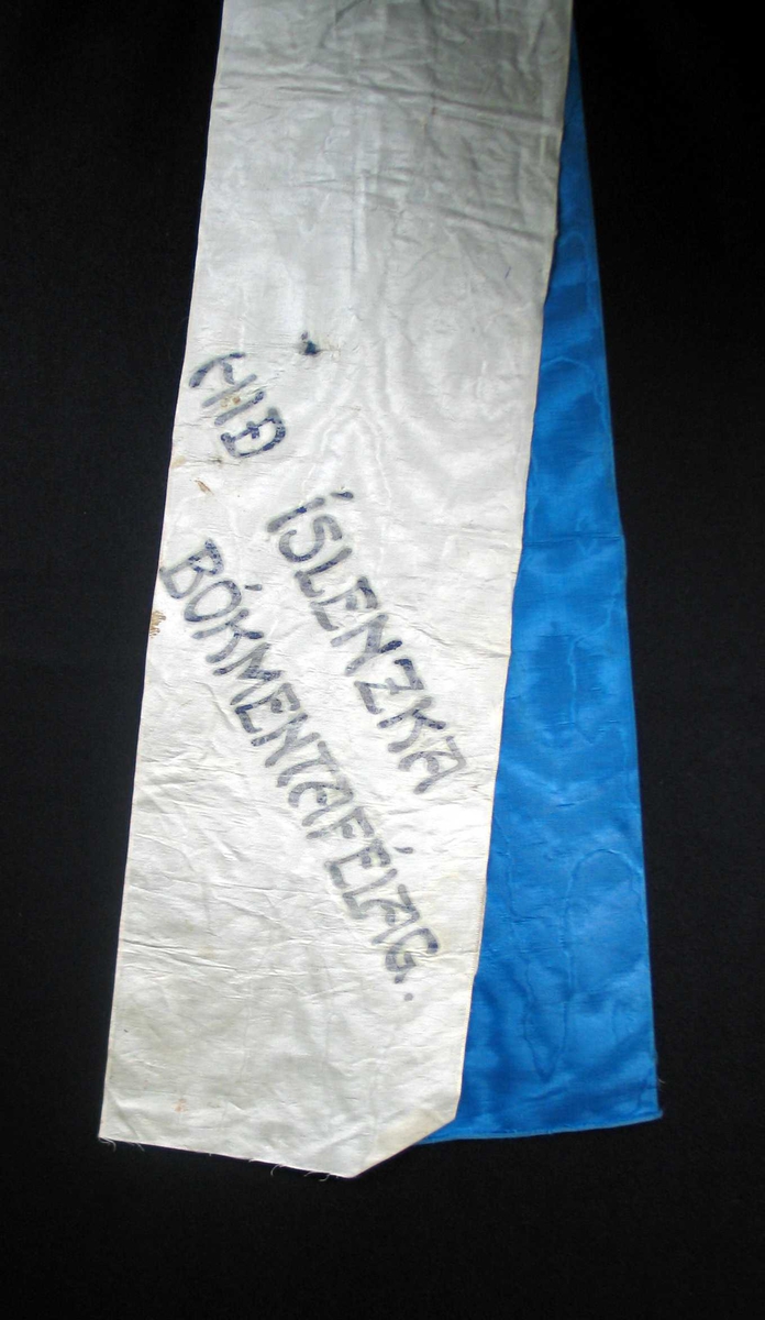 Begravelsessløyfe i hvit og blå silke med svart tekst.