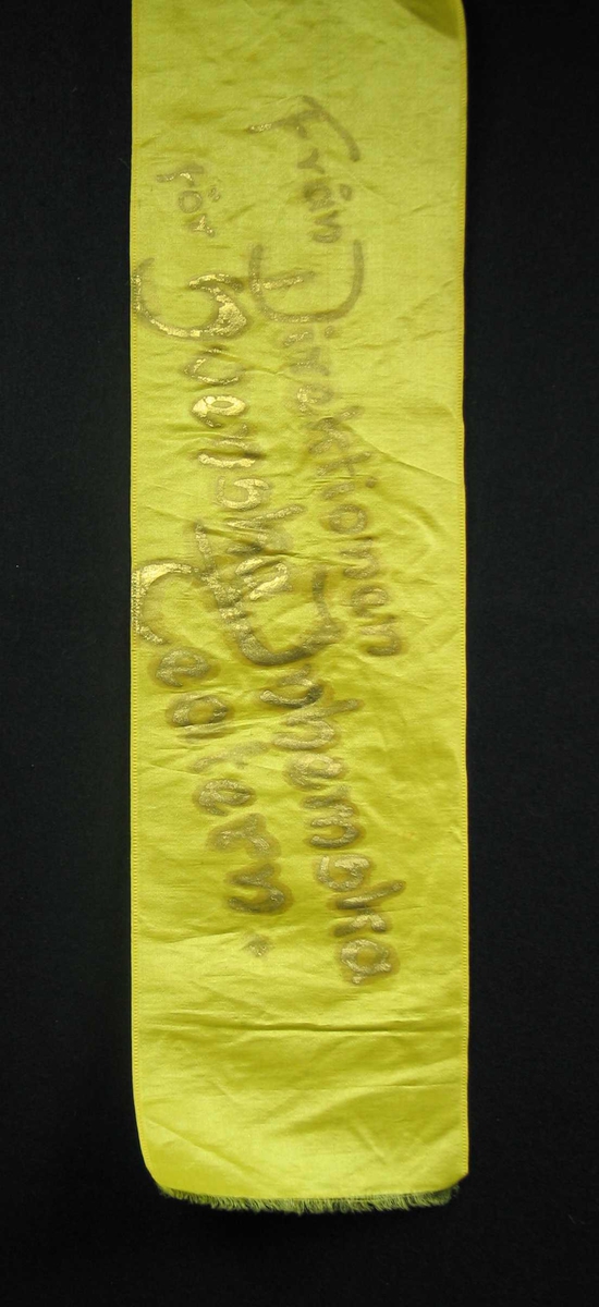 Begravelsessløyfe i lys grønn silke med tekst i gull.