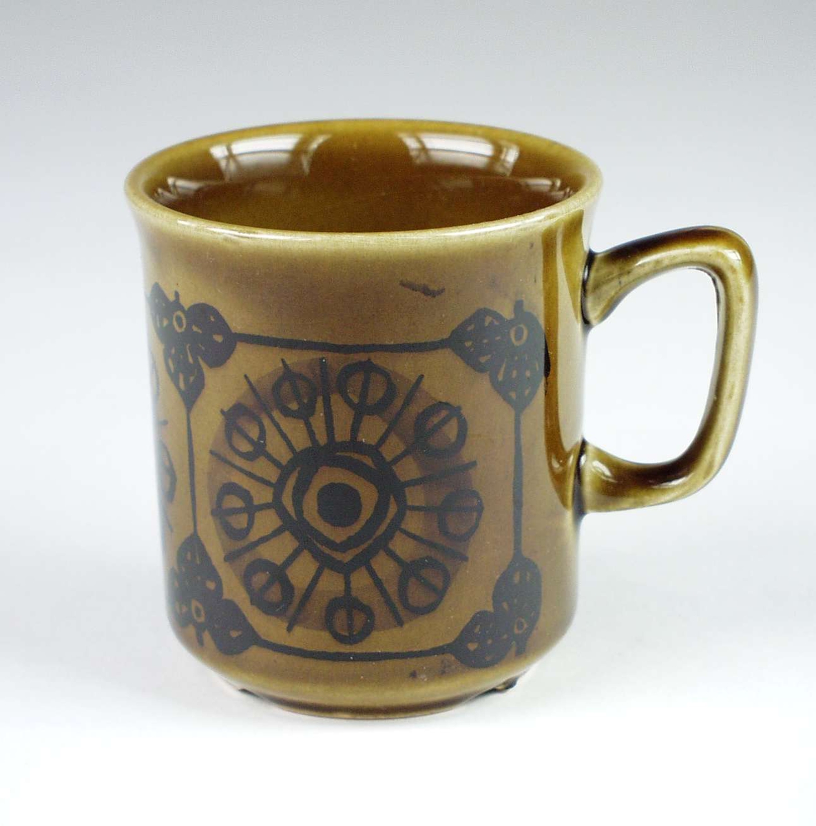 Syv brune kaffekopper i keramikk med mørk brun dekor. Serviset består ellers av elleve skåler og tolv asjetter.