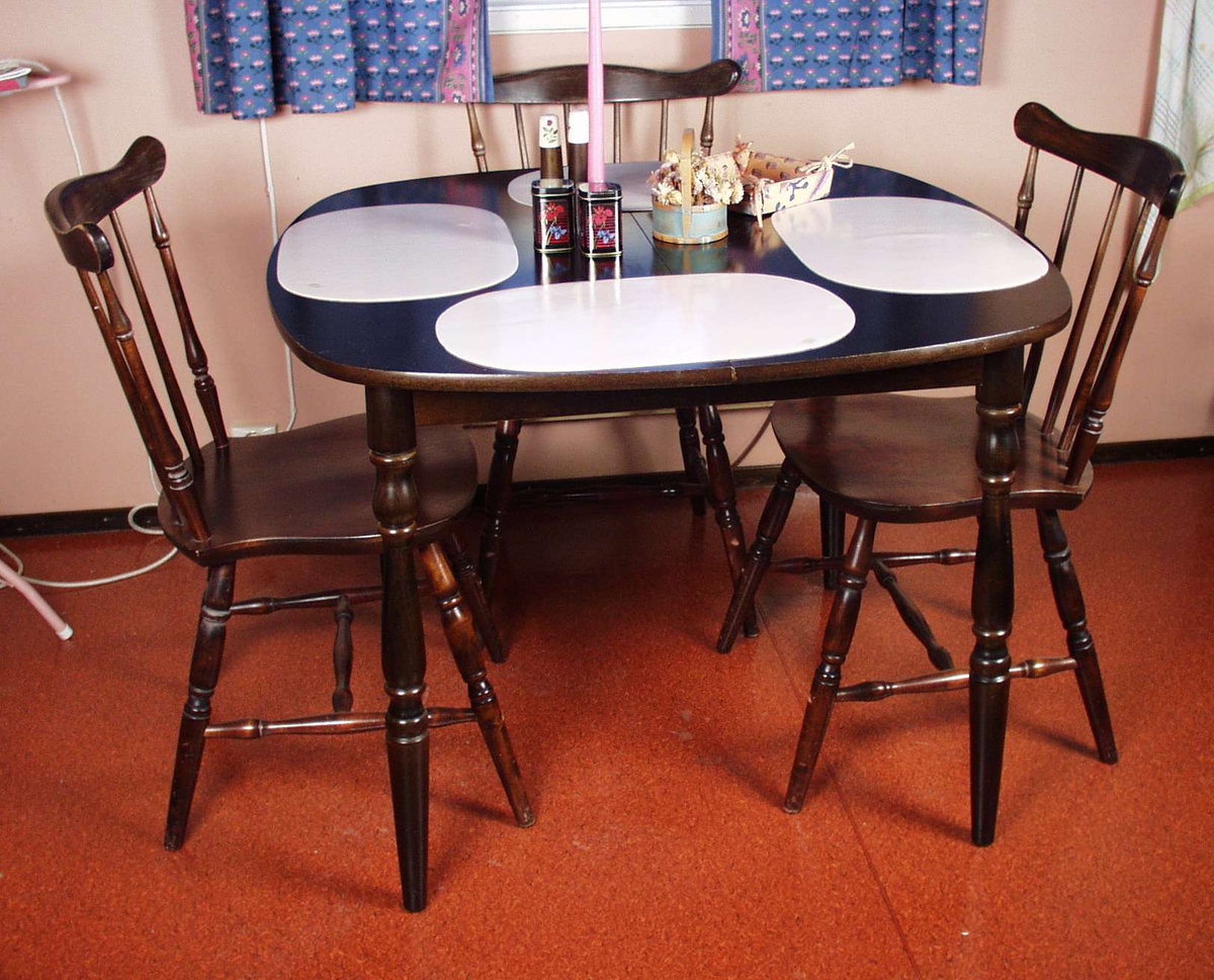 Kjøkkenbord i mørkt treverk med dreide ben. Bordet er firkantet med avrunda hjørner.