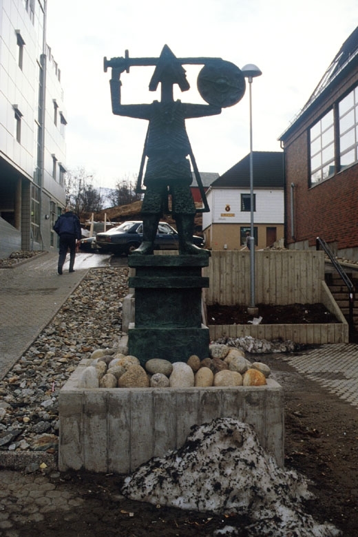 Skulpturen portretterer den historiske personen Torolv Kvedulvson som var grunnleggeren av Sandnessjøen.