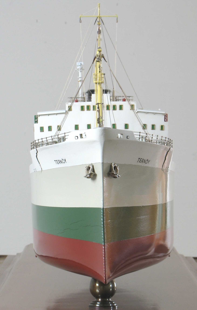 Skipsmodell, profesjonelt utført, montert på mahognyplate i glassmonter. Tankskipet  Ternøy", tilhørende Olaf Boes rederi, Arendal. Skroget malt lysgrått, grønt med rødbrun kjøl. På sort skorstein en hvit B.