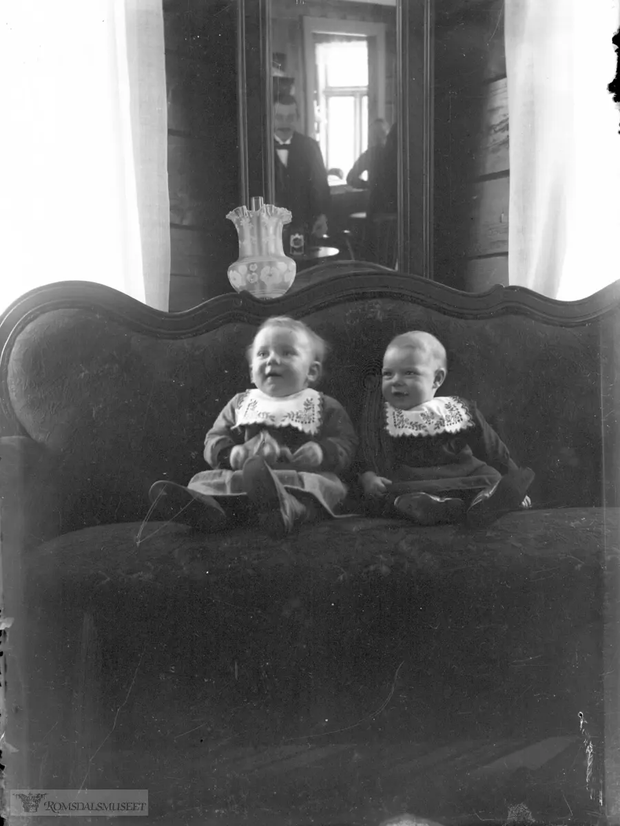Sigrid Pedersdatter Vike (f. 1913 g. Frisvoll) og Elen Aneusdatter Vike (f. 1913 g. Frisvoll) fotografert i stua på Våtåkeren. .Fotografen Otto Jæger ses i speilet i bakgrunnen.