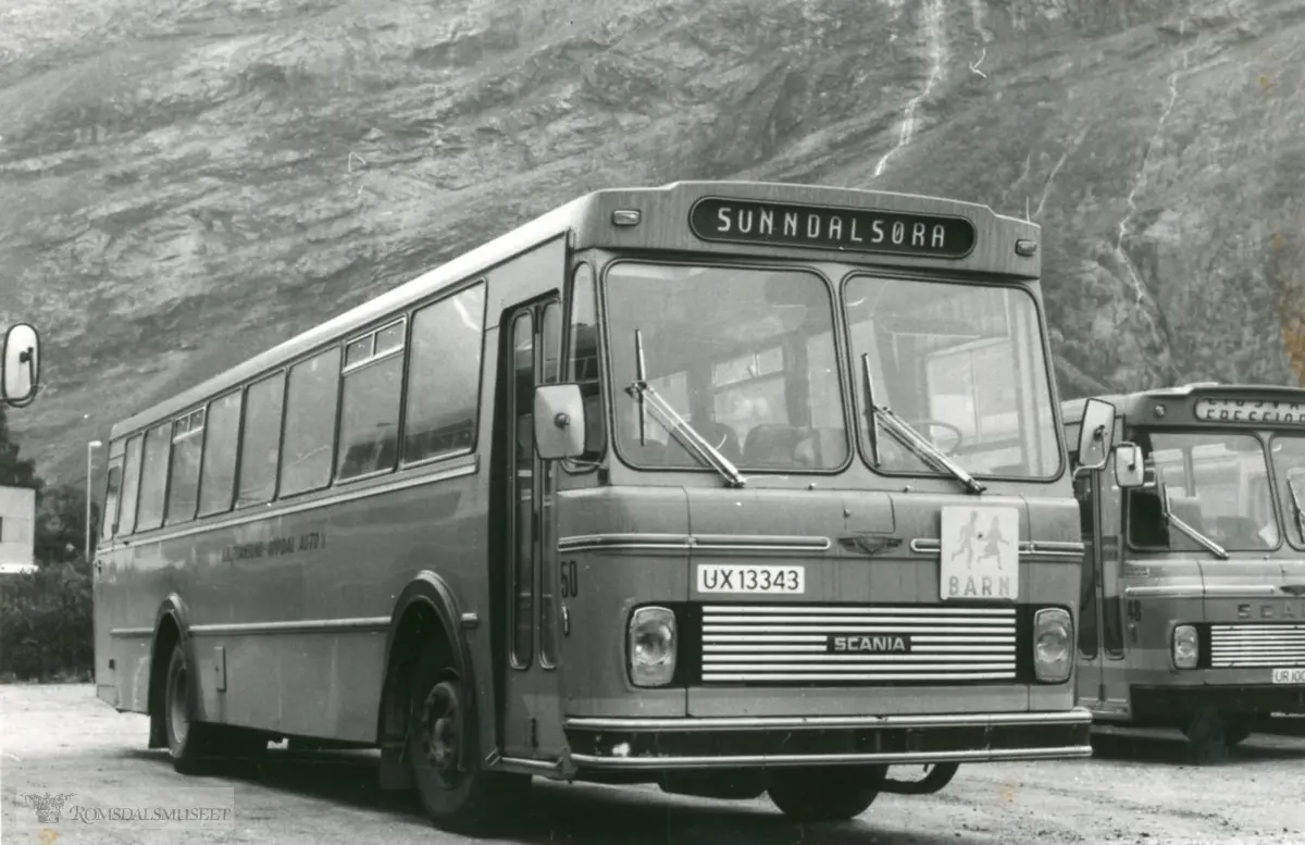 Kristiansund - Oppdal Auto A/S..Bussen til høyre på bildet er nok registrert UR10039. Det var en Scania BF110 med karosseri fra Kristiansund Lettmetall (VBK). Det er en 1971-modell som ble innkjøpt av Eira-Eidsvåg Billag (EEB). EEB ble i 1982 innlemmet i Kristiansund-Oppdal Auto (KOA). UR10039 ble med over til det nye selskapet og ble omlakkert til KOA sine farger. Av fargefordelingen kan man se at bildet er tatt etter omlakkeringen. UR10039 ble brukt som skolebuss utover 1980-tallet..(fra Oddbjørn Skjørsæter sine samlinger i Romsdalsarkivet)