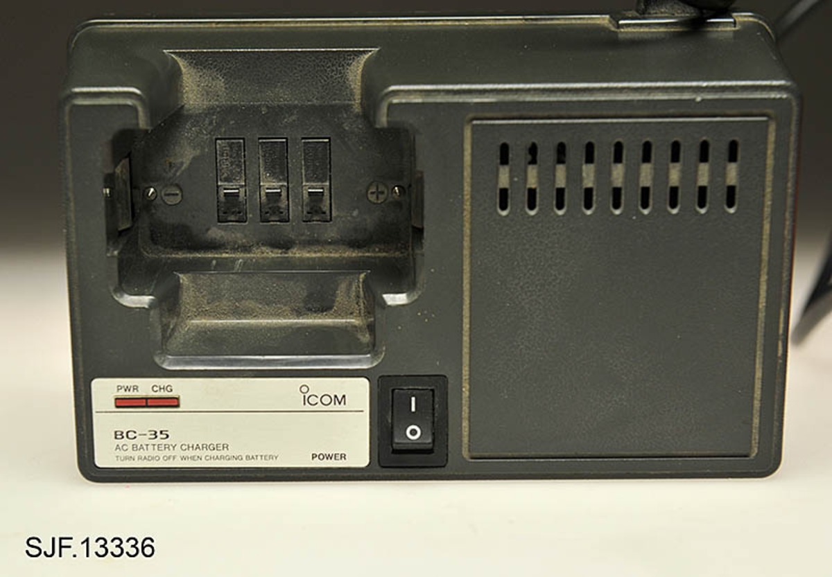 Denne kommunikasjonsradioen er en Icom IC-H12 med egen batterilader (ladestasjon). Radioen har fungert både som sikringsradio i skogbruket og som jaktradio. Det er installert ekstra kanaler for jakt (jaktkanaler) som dermed har muliggjort kombinasjonsbruk, skogbruk og jakt. Sikringskanalene er merket rødt.  Radioen har en rektangulær form, oransjefargede deksler og svart antenne. På toppdekslet er det montert tre knapper og en antenne. En kapp er kanalvelger, en annen er volumknapp og en tredje knapp (rød) for nødsending er merket med SQL. SQL merket indikerer trolig en mulighet for å regulere signalets styrke før høyttaleren åpner. På siden er det en svart knapp som brukes for sending og av meldinger. Under et gummideksel ved antenna er det mulighet for tilkobling av øretelefoner og mikrofon.  På baksiden er radioen utstyrt med en metallklype (10, 5 cm lang), slik at den lar seg feste i f. eks. et belte. Batteriladeren, BC-35, som følger med til radioen er utstyrt med en 160 cm lang ledning, slik at den kan kobles til en stikkontakt (220-240 volt). 
Det er påmontert fire gummiknotter på batteriladerens bunnplate. 