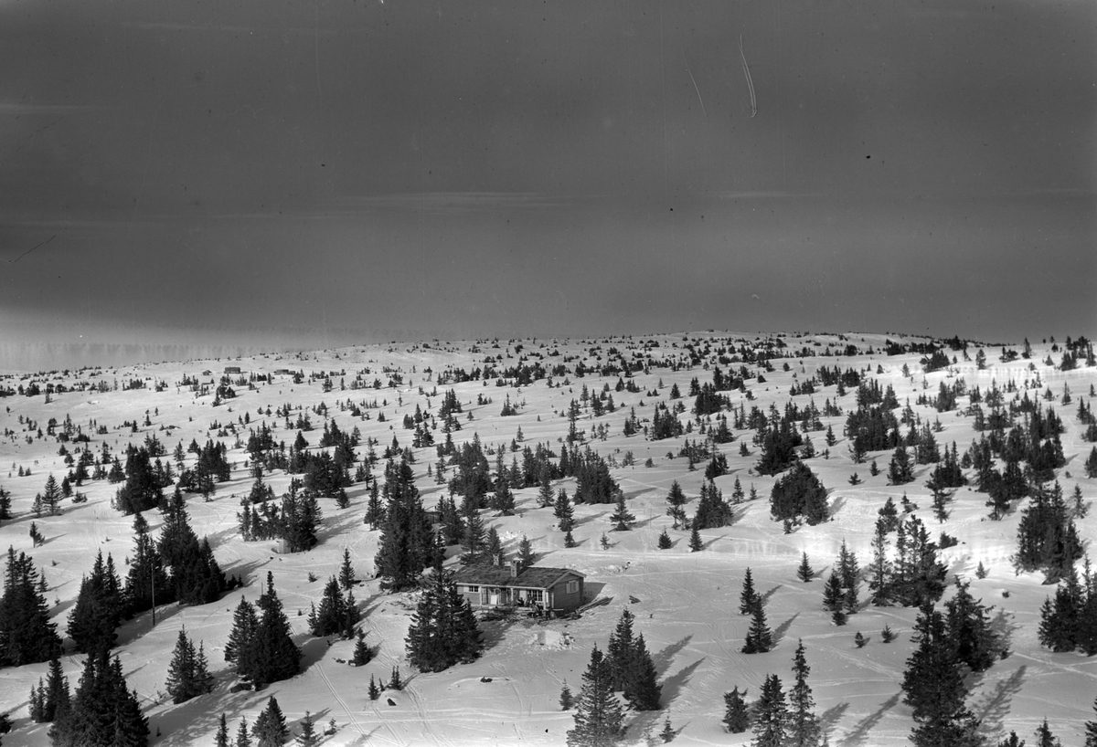 Flyfoto av hytte i vinterlandskap. Ukjent sted.