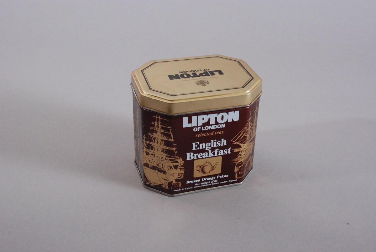 Fire seilskip i gull på brun bunn og en tekanne på hver av de to langsidene.. Tekst: "Lipton of London selected teas. English Breakfast. Broken Orange Pekoe".