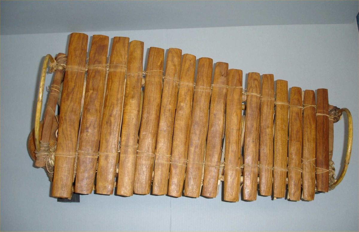 Xylofon med stativ av bambus og tre, satt sammen ved hjelp av lær-remser. 15 kalebass-staver henger i lær-remser, og danner resonans-korpus under selve xylofonen, som består av 16 staver av hardt brunt tre, festet til stativet med lær-remser. På siden av hver kalebass er et lite hull, som er dekket av membran (nå av papir, opprinnelig muligens av edderkoppegg).